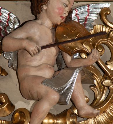 Zdjęcie nr 7: Parapet chóru muzycznego podtrzymywany przez dwie podpory. Balustrada na cokole, podzielona na cztery pola, wydzielone czterema pilastrami o trzonach w formie spływów wolutowych dekorowanych kampanulami i środkową hermą z półpostacią anioła. Pilastry podtrzymują niepełne belkowanie wyłamane na ich osi. Na belkowaniu, na osi skrajnych pilastrów wazony z kwiatami. W polach płyciny w formie leżącego prostokąta, ujęte profilowanymi ramami. W dwóch skrajnych płycinach przedstawienia instrumentów muzycznych ujętych rocaille&#039;m. Dwie środkowe płyciny z figurkami muzykujących puttów flankowanych rocaille&#039;m. Dolna krawędź balustrady, na osi środkowej dekorowana dwiema stykającymi się wolutami, przechodzącymi we wstęgę, ozdobioną rocaille&#039;m. Balustrada polichromowana w kolorze seledynowym, z kolorowymi profilami, ornamentyka i spływy wolutowe złocone i srebrzone. 


