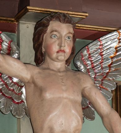 Zdjęcie nr 15: Parapet chóru muzycznego podtrzymywany przez dwie podpory. Balustrada na cokole, podzielona na cztery pola, wydzielone czterema pilastrami o trzonach w formie spływów wolutowych dekorowanych kampanulami i środkową hermą z półpostacią anioła. Pilastry podtrzymują niepełne belkowanie wyłamane na ich osi. Na belkowaniu, na osi skrajnych pilastrów wazony z kwiatami. W polach płyciny w formie leżącego prostokąta, ujęte profilowanymi ramami. W dwóch skrajnych płycinach przedstawienia instrumentów muzycznych ujętych rocaille&#039;m. Dwie środkowe płyciny z figurkami muzykujących puttów flankowanych rocaille&#039;m. Dolna krawędź balustrady, na osi środkowej dekorowana dwiema stykającymi się wolutami, przechodzącymi we wstęgę, ozdobioną rocaille&#039;m. Balustrada polichromowana w kolorze seledynowym, z kolorowymi profilami, ornamentyka i spływy wolutowe złocone i srebrzone. 


