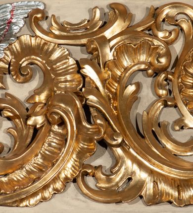 Zdjęcie nr 30: Parapet chóru muzycznego podtrzymywany przez dwie podpory. Balustrada na cokole, podzielona na cztery pola, wydzielone czterema pilastrami o trzonach w formie spływów wolutowych dekorowanych kampanulami i środkową hermą z półpostacią anioła. Pilastry podtrzymują niepełne belkowanie wyłamane na ich osi. Na belkowaniu, na osi skrajnych pilastrów wazony z kwiatami. W polach płyciny w formie leżącego prostokąta, ujęte profilowanymi ramami. W dwóch skrajnych płycinach przedstawienia instrumentów muzycznych ujętych rocaille'm. Dwie środkowe płyciny z figurkami muzykujących puttów flankowanych rocaille'm. Dolna krawędź balustrady, na osi środkowej dekorowana dwiema stykającymi się wolutami, przechodzącymi we wstęgę, ozdobioną rocaille'm. Balustrada polichromowana w kolorze seledynowym, z kolorowymi profilami, ornamentyka i spływy wolutowe złocone i srebrzone. 


