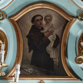 Zdjęcie nr 1: Obraz w formie zbliżonej do stojącego prostokąta zamkniętego łukiem falistym, o wklęsłych bokach. W centrum św. Antoni ukazany do kolan, zwrócony w trzech czwartych w lewo, z uniesioną głową, obiema rękami podtrzymuje Dzieciątko. Twarz ma szczupłą, o dużych, migdałowatych oczach w ciemnej oprawie, skierowanych w górę, prostym, wąskim nosie i pełnych, rozchylonych ustach; okoloną krótkimi, ciemnymi włosami, z tonsurą na głowie i aureolą ponad nią. Ubrany jest w brązowy habit z kapturem, przepasany w talii sznurem, z zawieszonym przy prawym boku różańcem. Dzieciątko w pozycji półsiedzącej, zwrócone w trzech czwartych w prawo, z głową ukazaną frontalnie, obiema rękami obejmuje św. Antoniego. Twarz ma pełną, o dużych, migdałowatych oczach, małym nosie i pełnych ustach; okoloną krótkimi, jasnymi włosami. Wokół głowy ma nimb. Owinięte jest białą tkaniną, odsłaniającą lewe ramię. W lewym dolnym rogu obrazu leżąca gałązka lilii. Postacie ukazane na cieniowanym brązowo-szarym tle. 