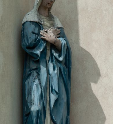 Zdjęcie nr 7: Grupa rzeźbiarska umieszczona we wnęce w formie stojącego prostokąta zamkniętego łukiem półkolistym. W centrum krzyż wypełniający całą wnękę, osadzony na skale, do którego trzema gwoździami przybita jest figura umarłego Chrystusa. Ciało ma w lekkim zwisie, o horyzontalnie rozłożonych ramionach, jego głowa opada na prawy bark, nogi ma lekko ugięte w kolanach, a stopy skrzyżowane w układzie prawa na lewą. Twarz ma szczupłą, o zamkniętych oczach, dużym nosie i otwartych ustach, okoloną krótką, kręconą brodą oraz falowanymi, brązowymi włosami, opadającymi na prawe ramię. Na głowie ma szeroką, brązową koronę cierniową. Ciało o lekko podkreślonej muskulaturze i silnie zaznaczonych żebrach klatki piersiowej. Przez biodra przewiązane krótkie, białe perizonium ze zwisem tkaniny na prawym boku. 
Po lewej stronie krzyża figura Marii, ustawiona na półkolistej podstawie. Matka Boska zwrócona w trzech czwartych w lewo, z pochyloną głową oraz rękami skrzyżowanymi na piersi. Twarz ma owalną, o dużych, migdałowatych oczach, dużym nosie i wąskich ustach. Ubrana jest w białą suknię oraz jasnoniebieski płaszcz z szerokimi rękawami, rozchylony z przodu, na głowę ma narzucony biały welon opadający na ramiona. 
Po prawej stronie krzyża figura św. Jana ustawiona na półkolistej podstawie. Święty zwrócony w trzech czwartych w prawo, w kontrapoście, z uniesionymi, splecionymi dłońmi. Twarz ma szczupłą, o migdałowatych oczach, prostym nosie i wąskich ustach, okoloną gęstymi, kręconymi, brązowymi włosami, opadającymi na ramiona. Ubrany jest w jasnoniebieską suknię oraz zawiązany diagonalnie przez prawe ramię czerwony płaszcz. Polichromia ciał naturalistyczna. 
