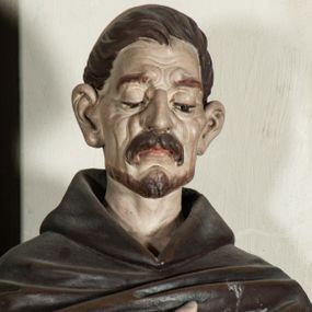 Zdjęcie nr 1: Rzeźba pełnoplastyczna, ustawiona na podstawie na planie prostokąta. Święty Dominik ukazany frontalnie, w kontrapoście, z pochyloną głową, prawą rękę kładzie na piersi, w lewej wyciągniętej do przodu trzyma różaniec. Twarz o wyraźnie zaznaczonych zmarszczkach, dużych uszach, zapadniętych policzkach, zmarszczonym czole, o dużych oczach skierowanych w dół, wydatnym nosie i wąskich ustach z gęstymi wąsami. Włosy ma krótkie, brązowe, z tonsurą na głowie. Święty ubrany jest w biały habit ze złoconą lamówką, przepasany w talii, z różowym szkaplerzem, na ramiona ma narzuconą brązową pelerynkę z kapturem i złoconą lamówką. Polichromia ciała naturalistyczna, o bladej karnacji. Przy lewej nodze świętego postać brązowego, leżącego psa. 



