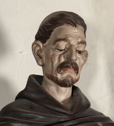 Zdjęcie nr 2: Rzeźba pełnoplastyczna, ustawiona na podstawie na planie prostokąta. Święty Dominik ukazany frontalnie, w kontrapoście, z pochyloną głową, prawą rękę kładzie na piersi, w lewej wyciągniętej do przodu trzyma różaniec. Twarz o wyraźnie zaznaczonych zmarszczkach, dużych uszach, zapadniętych policzkach, zmarszczonym czole, o dużych oczach skierowanych w dół, wydatnym nosie i wąskich ustach z gęstymi wąsami. Włosy ma krótkie, brązowe, z tonsurą na głowie. Święty ubrany jest w biały habit ze złoconą lamówką, przepasany w talii, z różowym szkaplerzem, na ramiona ma narzuconą brązową pelerynkę z kapturem i złoconą lamówką. Polichromia ciała naturalistyczna, o bladej karnacji. Przy lewej nodze świętego postać brązowego, leżącego psa. 



