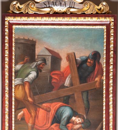 Zdjęcie nr 7: Stacje drogi krzyżowej zawieszone na ścianach bocznych nawy głównej. Obrazy w kształcie stojących prostokątów. W zwieńczeniu w kartuszu oplecionym rzeźbionymi liśćmi akantu malowane nazwy stacji, zapisane „STACYA I / STACYA II [...]”. U góry zakończone krzyżykiem łacińskim. Obrazy ujęte profilowaną ramą, zdobioną kimationem.  Kolorystyka żywa, z dominacją czerwieni i błękitu, plan dalszy rozmyty. Rama polichromowana na bordowo, profilowania i ornamentyka złocone, detale srebrzone.
