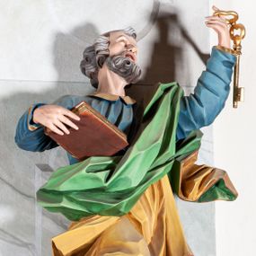 Zdjęcie nr 1: Rzeźba drążona, ścięta z tyłu, przedstawiająca św. Piotra. Święty ustawiony frontalnie, o esowato wygiętej sylwetce, z ugiętą prawą nogą, opartą o stopień. W lewej uniesionej wysoko ręce trzyma dwa klucze, prawą  podtrzymuje opartą o bok księgę. Głowa skierowana trzy czwarte w lewo i uniesiona w górę. Twarz ascetyczna, oczy uniesione w górę, rozchylone usta; okolona gęstą brodą, układającą się w pukle. Włosy siwe w postaci silnie skręconych loków po bokach i na tyle głowy oraz pukiel na czole. Święty ubrany jest w niebieską suknię z kołnierzykiem oraz przerzucony diagonalnie przez lewe ramię żółty płaszcz ze złoconą lamówką i zieloną podszewką. Tkanina ekspresyjnie kształtowana, silnie drapowana, miejscami przylegająca do ciała. Polichromia naturalistyczna, atrybuty i lamówka złocone.