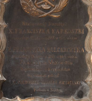Zdjęcie nr 1: Tablica w formie stojącego prostokąta ujęta w ramę o fantazyjnym zarysie, zwieńczona krzyżem. W górnej części odlany kielich z hostią ze skrzyżowanymi kotwicą i pochodnią, ujęte gałązkami palmy i mirtu. W polu złocona inskrypcja „Wdzięcznej Pamięci / X(IĘDZA) FRANCISZKA KARKOSZKI / zmarłego 26.  Marca 1847 w 41 z(ycia) wieku / i / X(IĘDZA) FRANCISZKA BALCARCZYKA / zmarłego 18. Czerwca 1849 w 44 z(ycia) wieku / Proboszczom Makowskim / Współbraciom i Przyjaciołom / ten kamień położył / X(IĄDZ) FRANCISZEK XAWERY CIESIELSKI / Pleban w Suchy.” 

