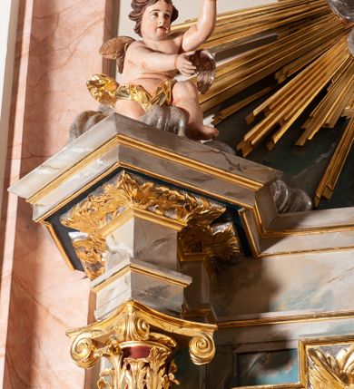 Zdjęcie nr 4: Ołtarz przyścienny, architektoniczny, jednoosiowy, jednokondygnacyjny ze zwieńczeniem. Mensa ołtarzowa skrzyniowa, prostopadłościenna z portatylem w formie kamiennej płytki. Antepedium współczesne, ujęte profilowaną ramą zdobioną żłobionym wałkiem, obite blachą miedzianą, na której odlewana, aplikowana dekoracja przedstawiająca w centrum Baranka Bożego w glorii promienistej z obłokami, po bokach dwie klęczące postacie kobiece, symbole ewangelistów oraz motywy kwiatowe. Tabernakulum w formie prostopadłościennej skrzynki, ustawione na cokole, zamknięte profilowanym gzymsem. Drzwiczki w kształcie stojącego prostokąta z malowanymi czterema scenami z życia Chrystusa. Narożniki obwiedzione złotymi listwami. Nastawa ołtarzowa umieszczona na podwójnym cokole, flankowana dwiema kolumnami, kanelowanymi od jednej czwartej wysokości o kapitelach kompozytowych, dźwigających pełne, wyłamane belkowanie oraz imposty ustawione pod kątem, na których znajduje się para puttów. Po zewnętrznej stronie kolumn cokoły z figurami św. Józefa z Dzieciątkiem po lewej i św. Anny z Marią po prawej. Pole środkowe w formie niszy w kształcie stojącego prostokąta o wciętych górnych narożach z pełnoplastyczną figurą Najświętszego Serca Jezusa. Zwieńczenie w formie promienistej glorii, z otoczonym obłokami medalionem w środku z gorejącym sercem. Cokoły figur i kolumn dekorowane płycinami z esowato wygiętym ornamentem roślinnym. Gzyms impostów zdobiony ornamentem roślinnym, w partii fryzu rzeźbiona uskrzydlona główka anielska. Rama w polu środkowym dekorowana płaskorzeźbionym ornamentem roślinnym. Struktura marmoryzowana w odcieniu różowo-błękitnym, detale architektoniczne polichromowane na niebiesko i czerwono, ornamentyka i profilowania pozłacane i posrebrzane.