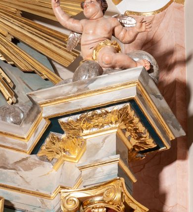 Zdjęcie nr 5: Ołtarz przyścienny, architektoniczny, jednoosiowy, jednokondygnacyjny ze zwieńczeniem. Mensa ołtarzowa skrzyniowa, prostopadłościenna z portatylem w formie kamiennej płytki. Antepedium współczesne, ujęte profilowaną ramą zdobioną żłobionym wałkiem, obite blachą miedzianą, na której odlewana, aplikowana dekoracja przedstawiająca w centrum Baranka Bożego w glorii promienistej z obłokami, po bokach dwie klęczące postacie kobiece, symbole ewangelistów oraz motywy kwiatowe. Tabernakulum w formie prostopadłościennej skrzynki, ustawione na cokole, zamknięte profilowanym gzymsem. Drzwiczki w kształcie stojącego prostokąta z malowanymi czterema scenami z życia Chrystusa. Narożniki obwiedzione złotymi listwami. Nastawa ołtarzowa umieszczona na podwójnym cokole, flankowana dwiema kolumnami, kanelowanymi od jednej czwartej wysokości o kapitelach kompozytowych, dźwigających pełne, wyłamane belkowanie oraz imposty ustawione pod kątem, na których znajduje się para puttów. Po zewnętrznej stronie kolumn cokoły z figurami św. Józefa z Dzieciątkiem po lewej i św. Anny z Marią po prawej. Pole środkowe w formie niszy w kształcie stojącego prostokąta o wciętych górnych narożach z pełnoplastyczną figurą Najświętszego Serca Jezusa. Zwieńczenie w formie promienistej glorii, z otoczonym obłokami medalionem w środku z gorejącym sercem. Cokoły figur i kolumn dekorowane płycinami z esowato wygiętym ornamentem roślinnym. Gzyms impostów zdobiony ornamentem roślinnym, w partii fryzu rzeźbiona uskrzydlona główka anielska. Rama w polu środkowym dekorowana płaskorzeźbionym ornamentem roślinnym. Struktura marmoryzowana w odcieniu różowo-błękitnym, detale architektoniczne polichromowane na niebiesko i czerwono, ornamentyka i profilowania pozłacane i posrebrzane.