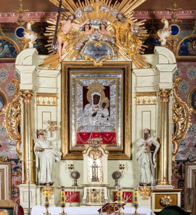 Zdjęcie nr 1: Nastawa ołtarzowa jednoosiowa, jednokondygnacyjna ze zwieńczeniem, na podwójnym cokole. W partii cokołu prostokątne płyciny, z których wewnętrzne są wypełnione wotami.  Mensa drewniana, wklęsło-wypukła. Kondygnacja nastawy ujęta szerokimi pilastrami o kapitelach zdobionych liśćmi akantu ustawionymi skośnie oraz stojącą przed nimi parą kolumn. Podpory dźwigają fragmenty pełnego belkowania wyłamanego na ich osiach; przerwanego nad polem środkowym. Kolumny podtrzymują przerwany przyczółek, na którym ustawiono fragmenty dekoracji rokokowej. Podpory ustawione zostały na profilowanych cokołach, po ich wewnętrznych stronach figury św. Piotra po lewej i św. Pawła po prawej stronie. W polu środkowym obraz z przedstawieniem Matki Boskiej Częstochowskiej w profilowanej ramie w kształcie stojącego prostokąta Nad nia kartusz z napisem „Regina Poloniae / ora pro nobis”. Kondygnacje ujmują uszaki z płomienistego rocaille’a.  Zwieńczenie tworzy rzeźbiarska grupa Trójcy świętej na obłokach, między którymi unoszą się uskrzydlone główki anielskie. Struktura polichromowana na kremowo, kolumny złocone, detale, profile i ornamenty złocone i srebrzone. 