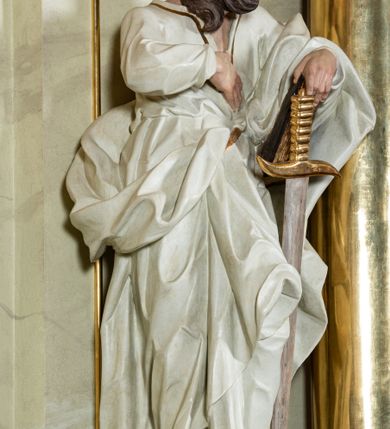 Zdjęcie nr 21: Nastawa ołtarzowa jednoosiowa, jednokondygnacyjna ze zwieńczeniem, na podwójnym cokole. W partii cokołu prostokątne płyciny, z których wewnętrzne są wypełnione wotami.  Mensa drewniana, wklęsło-wypukła. Kondygnacja nastawy ujęta szerokimi pilastrami o kapitelach zdobionych liśćmi akantu ustawionymi skośnie oraz stojącą przed nimi parą kolumn. Podpory dźwigają fragmenty pełnego belkowania wyłamanego na ich osiach; przerwanego nad polem środkowym. Kolumny podtrzymują przerwany przyczółek, na którym ustawiono fragmenty dekoracji rokokowej. Podpory ustawione zostały na profilowanych cokołach, po ich wewnętrznych stronach figury św. Piotra po lewej i św. Pawła po prawej stronie. W polu środkowym obraz z przedstawieniem Matki Boskiej Częstochowskiej w profilowanej ramie w kształcie stojącego prostokąta Nad nia kartusz z napisem „Regina Poloniae / ora pro nobis”. Kondygnacje ujmują uszaki z płomienistego rocaille’a.  Zwieńczenie tworzy rzeźbiarska grupa Trójcy świętej na obłokach, między którymi unoszą się uskrzydlone główki anielskie. Struktura polichromowana na kremowo, kolumny złocone, detale, profile i ornamenty złocone i srebrzone. 