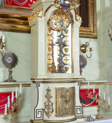 Zdjęcie nr 33: Nastawa ołtarzowa jednoosiowa, jednokondygnacyjna ze zwieńczeniem, na podwójnym cokole. W partii cokołu prostokątne płyciny, z których wewnętrzne są wypełnione wotami.  Mensa drewniana, wklęsło-wypukła. Kondygnacja nastawy ujęta szerokimi pilastrami o kapitelach zdobionych liśćmi akantu ustawionymi skośnie oraz stojącą przed nimi parą kolumn. Podpory dźwigają fragmenty pełnego belkowania wyłamanego na ich osiach; przerwanego nad polem środkowym. Kolumny podtrzymują przerwany przyczółek, na którym ustawiono fragmenty dekoracji rokokowej. Podpory ustawione zostały na profilowanych cokołach, po ich wewnętrznych stronach figury św. Piotra po lewej i św. Pawła po prawej stronie. W polu środkowym obraz z przedstawieniem Matki Boskiej Częstochowskiej w profilowanej ramie w kształcie stojącego prostokąta Nad nia kartusz z napisem „Regina Poloniae / ora pro nobis”. Kondygnacje ujmują uszaki z płomienistego rocaille’a.  Zwieńczenie tworzy rzeźbiarska grupa Trójcy świętej na obłokach, między którymi unoszą się uskrzydlone główki anielskie. Struktura polichromowana na kremowo, kolumny złocone, detale, profile i ornamenty złocone i srebrzone. 