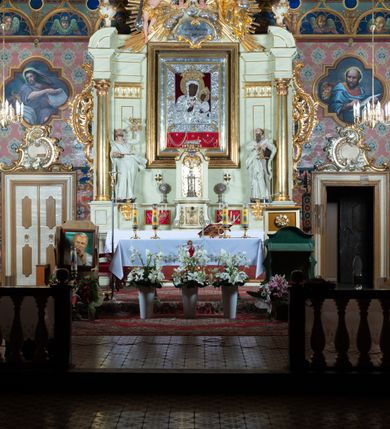 Zdjęcie nr 3: Nastawa ołtarzowa jednoosiowa, jednokondygnacyjna ze zwieńczeniem, na podwójnym cokole. W partii cokołu prostokątne płyciny, z których wewnętrzne są wypełnione wotami.  Mensa drewniana, wklęsło-wypukła. Kondygnacja nastawy ujęta szerokimi pilastrami o kapitelach zdobionych liśćmi akantu ustawionymi skośnie oraz stojącą przed nimi parą kolumn. Podpory dźwigają fragmenty pełnego belkowania wyłamanego na ich osiach; przerwanego nad polem środkowym. Kolumny podtrzymują przerwany przyczółek, na którym ustawiono fragmenty dekoracji rokokowej. Podpory ustawione zostały na profilowanych cokołach, po ich wewnętrznych stronach figury św. Piotra po lewej i św. Pawła po prawej stronie. W polu środkowym obraz z przedstawieniem Matki Boskiej Częstochowskiej w profilowanej ramie w kształcie stojącego prostokąta Nad nia kartusz z napisem „Regina Poloniae / ora pro nobis”. Kondygnacje ujmują uszaki z płomienistego rocaille’a.  Zwieńczenie tworzy rzeźbiarska grupa Trójcy świętej na obłokach, między którymi unoszą się uskrzydlone główki anielskie. Struktura polichromowana na kremowo, kolumny złocone, detale, profile i ornamenty złocone i srebrzone. 