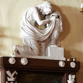 Zdjęcie nr 1: Wmurowany w ścianę kościoła nagrobek, na wysokim postumencie, z tablicą w kształcie leżącego prostokąta z czterema metalowymi ćwiekami w kształcie rozet, w szerokiej ramie z stiukowymi herbami Nowina i Bogoria na bokach i profilowanym gzymsem z czterema stiukowymi rozetami. Ponad gzymsem ukazana z prawego profilu klęcząca i wsparta na urnie kobieta, ubrana w togę i płaszcz zarzucony na głowę, plecy i częściowo zakrywający urnę, na której kobieta wspiera ręce i głowę. Twarz pełna, o delikatnych rysach i zamkniętych oczach. Włosy sięgające ramion, o gęstych, kręconych puklach. Urna w typie amfory greckiej zdobiona dołem szerokimi liśćmi i pięciopłatkowymi kwiatami, górą fryzem z liśćmi akantu. Na tablicy inskrypcja: "D(eo) O(ptimo) M(aximo) / Józefowi i Teressie Skotnickich / KONOPKOM. / Łowczym Sanockim / Rodzicom Dobrodziejom Naszym. / Teressie w dniu 15. Grudnia 1801. a Józefowi / d(nia) 27. Września 1811. R(oku) zmarłym / Pomnik kładziemy". 