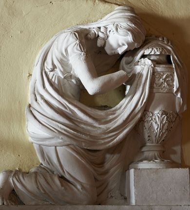 Zdjęcie nr 4: Wmurowany w ścianę kościoła nagrobek, na wysokim postumencie, z tablicą w kształcie leżącego prostokąta z czterema metalowymi ćwiekami w kształcie rozet, w szerokiej ramie z stiukowymi herbami Nowina i Bogoria na bokach i profilowanym gzymsem z czterema stiukowymi rozetami. Ponad gzymsem ukazana z prawego profilu klęcząca i wsparta na urnie kobieta, ubrana w togę i płaszcz zarzucony na głowę, plecy i częściowo zakrywający urnę, na której kobieta wspiera ręce i głowę. Twarz pełna, o delikatnych rysach i zamkniętych oczach. Włosy sięgające ramion, o gęstych, kręconych puklach. Urna w typie amfory greckiej zdobiona dołem szerokimi liśćmi i pięciopłatkowymi kwiatami, górą fryzem z liśćmi akantu. Na tablicy inskrypcja: "D(eo) O(ptimo) M(aximo) / Józefowi i Teressie Skotnickich / KONOPKOM. / Łowczym Sanockim / Rodzicom Dobrodziejom Naszym. / Teressie w dniu 15. Grudnia 1801. a Józefowi / d(nia) 27. Września 1811. R(oku) zmarłym / Pomnik kładziemy". 