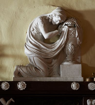 Zdjęcie nr 2: Wmurowany w ścianę kościoła nagrobek, na wysokim postumencie, z tablicą w kształcie leżącego prostokąta z czterema metalowymi ćwiekami w kształcie rozet, w szerokiej ramie z stiukowymi herbami Nowina i Bogoria na bokach i profilowanym gzymsem z czterema stiukowymi rozetami. Ponad gzymsem ukazana z prawego profilu klęcząca i wsparta na urnie kobieta, ubrana w togę i płaszcz zarzucony na głowę, plecy i częściowo zakrywający urnę, na której kobieta wspiera ręce i głowę. Twarz pełna, o delikatnych rysach i zamkniętych oczach. Włosy sięgające ramion, o gęstych, kręconych puklach. Urna w typie amfory greckiej zdobiona dołem szerokimi liśćmi i pięciopłatkowymi kwiatami, górą fryzem z liśćmi akantu. Na tablicy inskrypcja: "D(eo) O(ptimo) M(aximo) / Józefowi i Teressie Skotnickich / KONOPKOM. / Łowczym Sanockim / Rodzicom Dobrodziejom Naszym. / Teressie w dniu 15. Grudnia 1801. a Józefowi / d(nia) 27. Września 1811. R(oku) zmarłym / Pomnik kładziemy". 