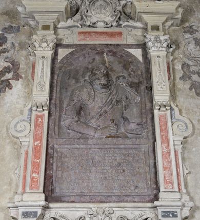 Zdjęcie nr 2: Epitafium w oprawie architektonicznej w formie aedikuli z płaskorzeźbioną półpostacią zmarłego oraz tablicą z inskrypcją; ujęte zdwojonymi pilastrami o kapitelach korynckich; trzony do połowy wysokości dekorowane płycinami, powyżej festonami i chwostami. Podpory dźwigają imposty zakończone cokołami z kulami. Zewnętrzne pilastry z wolutą w połowie wysokości. U spodu dwie woluty dekorowane perełkowaniem i kwiatami z szyszką w formie cokołu z kulą. Ponad niszą płyta ujęta wolutami. Całość zwieńczona kartuszem z herbem Odrowąż (?) flankowanym wolutami z labrami w postaci bujnej dekoracji roślinnej oraz płaskorzeźbiona figurą Chrystusa Zmartwychwstałego. O MORS CIELDELLIS? NVLLUM EST LIBIDIMINE DIGNA / NAM NVLLI PARCIT NVLLAQ(VE) DONA IVVANT.