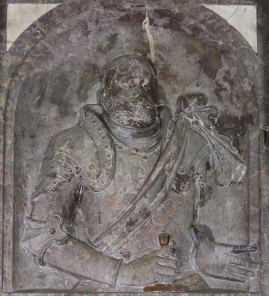 Zdjęcie nr 13: Epitafium w oprawie architektonicznej w formie aedikuli z płaskorzeźbioną półpostacią zmarłego oraz tablicą z inskrypcją; ujęte zdwojonymi pilastrami o kapitelach korynckich; trzony do połowy wysokości dekorowane płycinami, powyżej festonami i chwostami. Podpory dźwigają imposty zakończone cokołami z kulami. Zewnętrzne pilastry z wolutą w połowie wysokości. U spodu dwie woluty dekorowane perełkowaniem i kwiatami z szyszką w formie cokołu z kulą. Ponad niszą płyta ujęta wolutami. Całość zwieńczona kartuszem z herbem Odrowąż (?) flankowanym wolutami z labrami w postaci bujnej dekoracji roślinnej oraz płaskorzeźbiona figurą Chrystusa Zmartwychwstałego. O MORS CIELDELLIS? NVLLUM EST LIBIDIMINE DIGNA / NAM NVLLI PARCIT NVLLAQ(VE) DONA IVVANT.