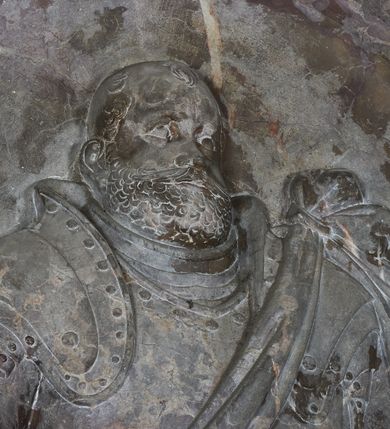 Zdjęcie nr 15: Epitafium w oprawie architektonicznej w formie aedikuli z płaskorzeźbioną półpostacią zmarłego oraz tablicą z inskrypcją; ujęte zdwojonymi pilastrami o kapitelach korynckich; trzony do połowy wysokości dekorowane płycinami, powyżej festonami i chwostami. Podpory dźwigają imposty zakończone cokołami z kulami. Zewnętrzne pilastry z wolutą w połowie wysokości. U spodu dwie woluty dekorowane perełkowaniem i kwiatami z szyszką w formie cokołu z kulą. Ponad niszą płyta ujęta wolutami. Całość zwieńczona kartuszem z herbem Odrowąż (?) flankowanym wolutami z labrami w postaci bujnej dekoracji roślinnej oraz płaskorzeźbiona figurą Chrystusa Zmartwychwstałego. O MORS CIELDELLIS? NVLLUM EST LIBIDIMINE DIGNA / NAM NVLLI PARCIT NVLLAQ(VE) DONA IVVANT.