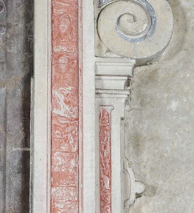 Zdjęcie nr 10: Epitafium w oprawie architektonicznej w formie aedikuli z płaskorzeźbioną półpostacią zmarłego oraz tablicą z inskrypcją; ujęte zdwojonymi pilastrami o kapitelach korynckich; trzony do połowy wysokości dekorowane płycinami, powyżej festonami i chwostami. Podpory dźwigają imposty zakończone cokołami z kulami. Zewnętrzne pilastry z wolutą w połowie wysokości. U spodu dwie woluty dekorowane perełkowaniem i kwiatami z szyszką w formie cokołu z kulą. Ponad niszą płyta ujęta wolutami. Całość zwieńczona kartuszem z herbem Odrowąż (?) flankowanym wolutami z labrami w postaci bujnej dekoracji roślinnej oraz płaskorzeźbiona figurą Chrystusa Zmartwychwstałego. O MORS CIELDELLIS? NVLLUM EST LIBIDIMINE DIGNA / NAM NVLLI PARCIT NVLLAQ(VE) DONA IVVANT.