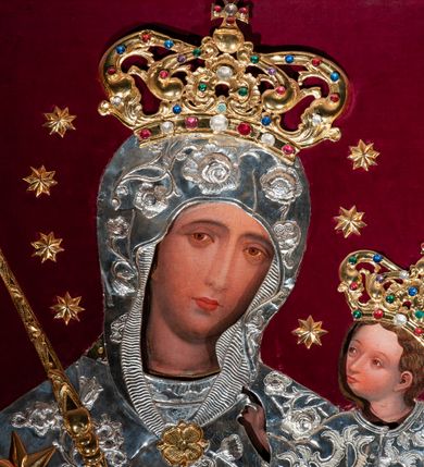 Zdjęcie nr 3: Metalowa sukienka na obraz Matki Boskiej z Dzieciątkiem w ołtarzu głównym, w kształcie obrysu sylwetek Marii i Dzieciątka, z otworami na twarze, dłonie i stopy Jezusa, zdobiona dekoracją roślinną i sześcioramienną złotą gwiazdą umieszczoną na prawym ramieniu Marii. W prawym dolnym narożu fragment sukienki o odmiennej dekoracji (być może pozostałość ze starszej sukienki). Korony w typie zamkniętym, zwieńczone krzyżykami, złocone, kameryzowane. Wokół głowy Matki Boskiej wieniec z gwiazd, w ręku złocone berło. Tło z nowego czerwonego aksamitu.