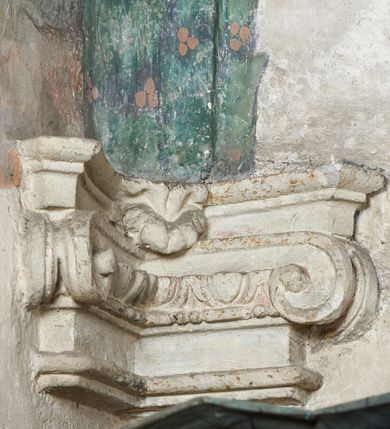 Zdjęcie nr 12: Strukturę architektoniczną kaplicy, wzniesionej na rzucie kwadratu ze ściętymi od północy narożami i sklepionej krzyżowo z lunetami spływającymi na wsporniki w kształcie kapiteli jońskich, podkreśla ornament złożony z motywów roślinnych. Szwy sklepienne pokrywa wić z liści i owoców wawrzynu miejscami przewiązana skrzyżowaną wstęgą. Pola sklepienia wypełniają medaliony z przedstawieniami czterech ewangelistów w ramach zdobionych ornamentem okuciowym, dzbany z kwiatami lilii, z uszami o motywach antropomorficznych oraz wici roślinne m. in. z motywami kwiatów lilii, falującymi wstęgami, zwisami z owoców oraz z tkaninami. Na ścianach sceny: Św. Stanisław wskrzeszający Piotrowina, Św. Wojciech, Przemienienie Pańskie na górze Tabor oraz kartusze herbowe. Kolorystyka pastelowa z przewagą zieleni, czerwieni i beżu.