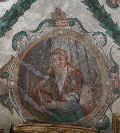 Zdjęcie nr 13: Strukturę architektoniczną kaplicy, wzniesionej na rzucie kwadratu ze ściętymi od północy narożami i sklepionej krzyżowo z lunetami spływającymi na wsporniki w kształcie kapiteli jońskich, podkreśla ornament złożony z motywów roślinnych. Szwy sklepienne pokrywa wić z liści i owoców wawrzynu miejscami przewiązana skrzyżowaną wstęgą. Pola sklepienia wypełniają medaliony z przedstawieniami czterech ewangelistów w ramach zdobionych ornamentem okuciowym, dzbany z kwiatami lilii, z uszami o motywach antropomorficznych oraz wici roślinne m. in. z motywami kwiatów lilii, falującymi wstęgami, zwisami z owoców oraz z tkaninami. Na ścianach sceny: Św. Stanisław wskrzeszający Piotrowina, Św. Wojciech, Przemienienie Pańskie na górze Tabor oraz kartusze herbowe. Kolorystyka pastelowa z przewagą zieleni, czerwieni i beżu.