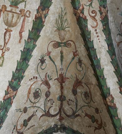 Zdjęcie nr 18: Strukturę architektoniczną kaplicy, wzniesionej na rzucie kwadratu ze ściętymi od północy narożami i sklepionej krzyżowo z lunetami spływającymi na wsporniki w kształcie kapiteli jońskich, podkreśla ornament złożony z motywów roślinnych. Szwy sklepienne pokrywa wić z liści i owoców wawrzynu miejscami przewiązana skrzyżowaną wstęgą. Pola sklepienia wypełniają medaliony z przedstawieniami czterech ewangelistów w ramach zdobionych ornamentem okuciowym, dzbany z kwiatami lilii, z uszami o motywach antropomorficznych oraz wici roślinne m. in. z motywami kwiatów lilii, falującymi wstęgami, zwisami z owoców oraz z tkaninami. Na ścianach sceny: Św. Stanisław wskrzeszający Piotrowina, Św. Wojciech, Przemienienie Pańskie na górze Tabor oraz kartusze herbowe. Kolorystyka pastelowa z przewagą zieleni, czerwieni i beżu.