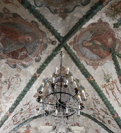 Zdjęcie nr 2: Strukturę architektoniczną kaplicy, wzniesionej na rzucie kwadratu ze ściętymi od północy narożami i sklepionej krzyżowo z lunetami spływającymi na wsporniki w kształcie kapiteli jońskich, podkreśla ornament złożony z motywów roślinnych. Szwy sklepienne pokrywa wić z liści i owoców wawrzynu miejscami przewiązana skrzyżowaną wstęgą. Pola sklepienia wypełniają medaliony z przedstawieniami czterech ewangelistów w ramach zdobionych ornamentem okuciowym, dzbany z kwiatami lilii, z uszami o motywach antropomorficznych oraz wici roślinne m. in. z motywami kwiatów lilii, falującymi wstęgami, zwisami z owoców oraz z tkaninami. Na ścianach sceny: Św. Stanisław wskrzeszający Piotrowina, Św. Wojciech, Przemienienie Pańskie na górze Tabor oraz kartusze herbowe. Kolorystyka pastelowa z przewagą zieleni, czerwieni i beżu.