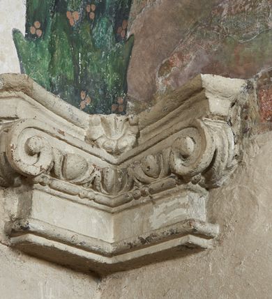 Zdjęcie nr 11: Strukturę architektoniczną kaplicy, wzniesionej na rzucie kwadratu ze ściętymi od północy narożami i sklepionej krzyżowo z lunetami spływającymi na wsporniki w kształcie kapiteli jońskich, podkreśla ornament złożony z motywów roślinnych. Szwy sklepienne pokrywa wić z liści i owoców wawrzynu miejscami przewiązana skrzyżowaną wstęgą. Pola sklepienia wypełniają medaliony z przedstawieniami czterech ewangelistów w ramach zdobionych ornamentem okuciowym, dzbany z kwiatami lilii, z uszami o motywach antropomorficznych oraz wici roślinne m. in. z motywami kwiatów lilii, falującymi wstęgami, zwisami z owoców oraz z tkaninami. Na ścianach sceny: Św. Stanisław wskrzeszający Piotrowina, Św. Wojciech, Przemienienie Pańskie na górze Tabor oraz kartusze herbowe. Kolorystyka pastelowa z przewagą zieleni, czerwieni i beżu.