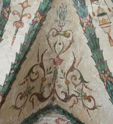 Zdjęcie nr 21: Strukturę architektoniczną kaplicy, wzniesionej na rzucie kwadratu ze ściętymi od północy narożami i sklepionej krzyżowo z lunetami spływającymi na wsporniki w kształcie kapiteli jońskich, podkreśla ornament złożony z motywów roślinnych. Szwy sklepienne pokrywa wić z liści i owoców wawrzynu miejscami przewiązana skrzyżowaną wstęgą. Pola sklepienia wypełniają medaliony z przedstawieniami czterech ewangelistów w ramach zdobionych ornamentem okuciowym, dzbany z kwiatami lilii, z uszami o motywach antropomorficznych oraz wici roślinne m. in. z motywami kwiatów lilii, falującymi wstęgami, zwisami z owoców oraz z tkaninami. Na ścianach sceny: Św. Stanisław wskrzeszający Piotrowina, Św. Wojciech, Przemienienie Pańskie na górze Tabor oraz kartusze herbowe. Kolorystyka pastelowa z przewagą zieleni, czerwieni i beżu.