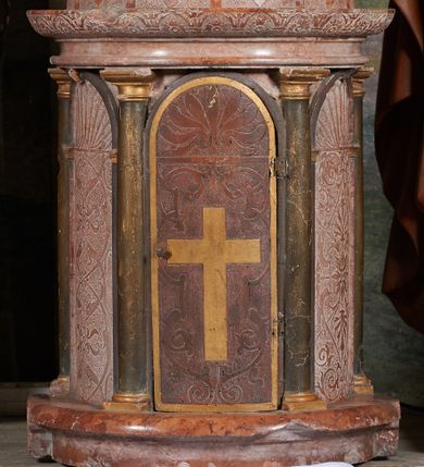 Zdjęcie nr 1: Tabernakulum na rzucie półkoła, na profilowanej podstawie, na której drewniane toskańskie kolumny podtrzymujące belkowanie z wydatnym gzymsem ozdobionym gładkimi arkadkami wypełnionymi rozetkami. Między kolumnami półkoliście zakończone drewniane arkady wypełnione ściankami. W środkowej, drewnianej, imitującej marmur, pełniącej funkcję drzwiczek, intarsjowany krzyż z jasnego drewna, otoczony symetryczną dekoracją z gładką wicią roślinną i palmetą w podłuczu.Ścianki boczne marmurowe z dekoracją groteskową (wicie arabeski przechodzące w abstrakcyjne głowy ptaków) i stylizowaną muszlą palmetową w podłuczu. Kopuła pokryta gładkimi żebrami prowadzonymi dośrodkowo, między którymi dekoracja roślinno-geometryczna.