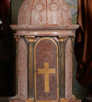 Zdjęcie nr 2: Tabernakulum na rzucie półkoła, na profilowanej podstawie, na której drewniane toskańskie kolumny podtrzymujące belkowanie z wydatnym gzymsem ozdobionym gładkimi arkadkami wypełnionymi rozetkami. Między kolumnami półkoliście zakończone drewniane arkady wypełnione ściankami. W środkowej, drewnianej, imitującej marmur, pełniącej funkcję drzwiczek, intarsjowany krzyż z jasnego drewna, otoczony symetryczną dekoracją z gładką wicią roślinną i palmetą w podłuczu.Ścianki boczne marmurowe z dekoracją groteskową (wicie arabeski przechodzące w abstrakcyjne głowy ptaków) i stylizowaną muszlą palmetową w podłuczu. Kopuła pokryta gładkimi żebrami prowadzonymi dośrodkowo, między którymi dekoracja roślinno-geometryczna.