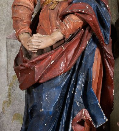 Zdjęcie nr 3: W centrum krzyż z figurą Chrystusa umarłego. Postać w lekkim zwisie o szeroko rozłożonych ramionach, głowa opada na prawe ramie. Twarz szczupła, wyraźnie rzeźbiona, okolona krótką brodą; oczy zamknięte, długi nos, usta delikatnie rozchylone. Włosy w postaci delikatnych loków opadają na ramię i plecy. Ciało szczupłe, ascetyczne, o plastycznie kształtowanej anatomii, z zaznaczonymi śladami męki. Nogi ugięte w kolanach, stopy przebite jednym gwoździem, założone prawa na lewą. Perizonium przewiązane podwójnym sznurem, odsłaniające prawe biodro, ze zwisem na prawym boku. Po prawej stronie krzyża figura Matki Boskiej, zwrócona en face, w kontrapoście; dłonie splecione, wyciągnięte przed siebie. Twarz okrągła o wyraźnych liniach łuków brwiowych i nosa, półprzymkniętych oczach. Ubrana w różową suknię przewiązaną w talii oraz granatowy płaszcz podbity czerwoną podszewką, zarzucony diagonalnie na lewe ramię i opadający na prawą nogę. Na głowie biały welon. Po lewej stronie krzyża figura św. Jana, zwrócona en face, w kontrapoście, o esowato wygiętej sylwetce; prawą rękę trzyma na piersi, lewa pozostaje opuszczona wzdłuż ciała. Twarz pełna, młodzieńcza, podkreślone linie łuków brwiowych i nosa. Włosy długie, falowane, opadają na ramiona. Ubrany w zieloną tunikę oraz czerwony płaszcz przerzucony diagonalnie przez prawy bok, przewiązane w talii. Polichromia naturalistyczna, perizonium złocone.Grupa na tle malowanego miasta oraz skłębionego szaroróżowego nieba.