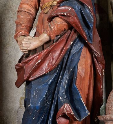 Zdjęcie nr 20: W centrum krzyż z figurą Chrystusa umarłego. Postać w lekkim zwisie o szeroko rozłożonych ramionach, głowa opada na prawe ramie. Twarz szczupła, wyraźnie rzeźbiona, okolona krótką brodą; oczy zamknięte, długi nos, usta delikatnie rozchylone. Włosy w postaci delikatnych loków opadają na ramię i plecy. Ciało szczupłe, ascetyczne, o plastycznie kształtowanej anatomii, z zaznaczonymi śladami męki. Nogi ugięte w kolanach, stopy przebite jednym gwoździem, założone prawa na lewą. Perizonium przewiązane podwójnym sznurem, odsłaniające prawe biodro, ze zwisem na prawym boku. Po prawej stronie krzyża figura Matki Boskiej, zwrócona en face, w kontrapoście; dłonie splecione, wyciągnięte przed siebie. Twarz okrągła o wyraźnych liniach łuków brwiowych i nosa, półprzymkniętych oczach. Ubrana w różową suknię przewiązaną w talii oraz granatowy płaszcz podbity czerwoną podszewką, zarzucony diagonalnie na lewe ramię i opadający na prawą nogę. Na głowie biały welon. Po lewej stronie krzyża figura św. Jana, zwrócona en face, w kontrapoście, o esowato wygiętej sylwetce; prawą rękę trzyma na piersi, lewa pozostaje opuszczona wzdłuż ciała. Twarz pełna, młodzieńcza, podkreślone linie łuków brwiowych i nosa. Włosy długie, falowane, opadają na ramiona. Ubrany w zieloną tunikę oraz czerwony płaszcz przerzucony diagonalnie przez prawy bok, przewiązane w talii. Polichromia naturalistyczna, perizonium złocone.Grupa na tle malowanego miasta oraz skłębionego szaroróżowego nieba.