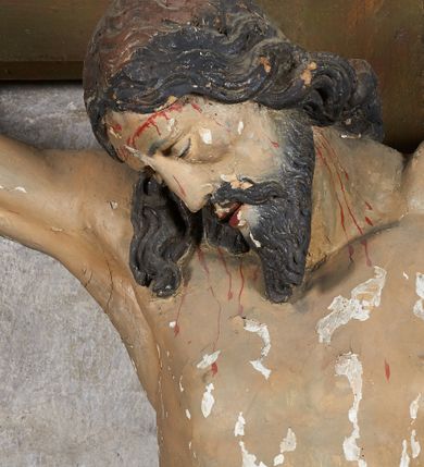 Zdjęcie nr 17: W centrum krzyż z figurą Chrystusa umarłego. Postać w lekkim zwisie o szeroko rozłożonych ramionach, głowa opada na prawe ramie. Twarz szczupła, wyraźnie rzeźbiona, okolona krótką brodą; oczy zamknięte, długi nos, usta delikatnie rozchylone. Włosy w postaci delikatnych loków opadają na ramię i plecy. Ciało szczupłe, ascetyczne, o plastycznie kształtowanej anatomii, z zaznaczonymi śladami męki. Nogi ugięte w kolanach, stopy przebite jednym gwoździem, założone prawa na lewą. Perizonium przewiązane podwójnym sznurem, odsłaniające prawe biodro, ze zwisem na prawym boku. Po prawej stronie krzyża figura Matki Boskiej, zwrócona en face, w kontrapoście; dłonie splecione, wyciągnięte przed siebie. Twarz okrągła o wyraźnych liniach łuków brwiowych i nosa, półprzymkniętych oczach. Ubrana w różową suknię przewiązaną w talii oraz granatowy płaszcz podbity czerwoną podszewką, zarzucony diagonalnie na lewe ramię i opadający na prawą nogę. Na głowie biały welon. Po lewej stronie krzyża figura św. Jana, zwrócona en face, w kontrapoście, o esowato wygiętej sylwetce; prawą rękę trzyma na piersi, lewa pozostaje opuszczona wzdłuż ciała. Twarz pełna, młodzieńcza, podkreślone linie łuków brwiowych i nosa. Włosy długie, falowane, opadają na ramiona. Ubrany w zieloną tunikę oraz czerwony płaszcz przerzucony diagonalnie przez prawy bok, przewiązane w talii. Polichromia naturalistyczna, perizonium złocone.Grupa na tle malowanego miasta oraz skłębionego szaroróżowego nieba.