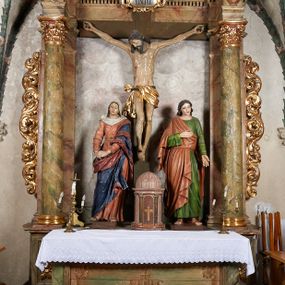 Zdjęcie nr 1: Ołtarz architektoniczny, jednoosiowy, jednokondygnacyjny, ze zwieńczeniem. Mensa drewniana z marmurowym portatylem, na prostopadłościennej skrzyni. Antepedium ujęte profilowaną ramą z malowanym obramieniem w polu oraz literami IHS. Retabulum ujęte parą kolumn o kapitelach kompozytowych, na cokołach, dźwigających występujące nad podporami pełne belkowanie i wydatny gzyms oraz przerwany półkolisty przyczółek. W polu środkowym rzeźbiona Grupa Ukrzyżowania na malowanym tle. W zwieńczeniu serce gorejące w glorii promienistej. Zwieńczenie ujęte spływami wolutowymi i cęgami, zamknięte gzymsem wygiętym łukiem odcinkowym. Cokoły kolumn zdobione płycinami z dekoracją roślinną. Nastawa flankowana uszami utworzonymi z motywów mięsistego akantu. Fryz dekorowany uskrzydlonymi główkami anielskimi. Nastawa i antepedium marmoryzowane w odcieniach seledynowych i beżoworóżowych, detale architektoniczne i ornamentyka złocone.
