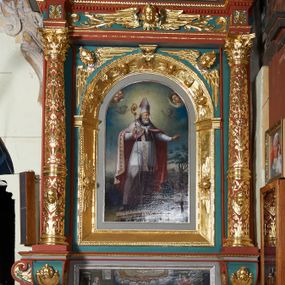 Zdjęcie nr 1: Ołtarz architektoniczny, jednokondygnacyjny. Mensa drewniana na murowanej prostopadłościennej skrzyni. Antepedium w kształcie prostokąta, w profilowanej ramie, z płaskorzeźbionymi splecionymi literami imienia Maria pośrodku i dwiema uskrzydlonymi główkami aniołków w górnych narożach. Retabulum z wydzieloną predellą ujętą po bokach konsolkami, flankowane parą kolumn. Kolumny o kapitelach korynckich i trzonach dekorowanych wicią roślinną, w jednej trzeciej wysokości przedzielone opaską. Kolumny wspierają wyłamane belkowanie zwieńczone profilowanym gzymsem. W polu środkowym prostokątna nisza zamknięta łukiem półkolistym, ujęta szeroką, złoconą ramą zdobioną uskrzydlonymi główkami aniołków. W polu niszy obraz z przedstawieniem św. Wojciecha. Predella dekorowana płyciną z malowaną sceną z przedstawieniem Zwiastowania NMP. Konsole kolumn i flankujące nastawę dekorowane na krawędziach wolutowo skręconą wicią roślinną. Belkowanie zdobione rozetami, w partii fryzu pośrodku aplikowana rzeźbiona uskrzydlona główka anielska. Całość struktury polichromowana w dwóch odcieniach: jasnobłękitnym oraz brązowym, detal architektoniczny i profilowania złocone i srebrzone.