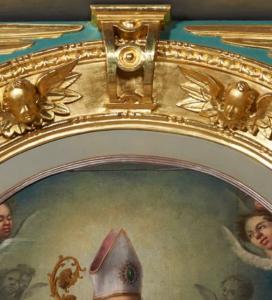 Zdjęcie nr 5: Ołtarz architektoniczny, jednokondygnacyjny. Mensa drewniana na murowanej prostopadłościennej skrzyni. Antepedium w kształcie prostokąta, w profilowanej ramie, z płaskorzeźbionymi splecionymi literami imienia Maria pośrodku i dwiema uskrzydlonymi główkami aniołków w górnych narożach. Retabulum z wydzieloną predellą ujętą po bokach konsolkami, flankowane parą kolumn. Kolumny o kapitelach korynckich i trzonach dekorowanych wicią roślinną, w jednej trzeciej wysokości przedzielone opaską. Kolumny wspierają wyłamane belkowanie zwieńczone profilowanym gzymsem. W polu środkowym prostokątna nisza zamknięta łukiem półkolistym, ujęta szeroką, złoconą ramą zdobioną uskrzydlonymi główkami aniołków. W polu niszy obraz z przedstawieniem św. Wojciecha. Predella dekorowana płyciną z malowaną sceną z przedstawieniem Zwiastowania NMP. Konsole kolumn i flankujące nastawę dekorowane na krawędziach wolutowo skręconą wicią roślinną. Belkowanie zdobione rozetami, w partii fryzu pośrodku aplikowana rzeźbiona uskrzydlona główka anielska. Całość struktury polichromowana w dwóch odcieniach: jasnobłękitnym oraz brązowym, detal architektoniczny i profilowania złocone i srebrzone.