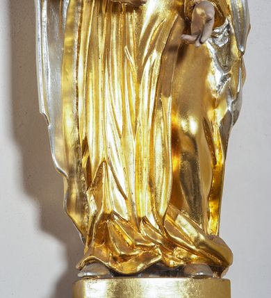 Zdjęcie nr 2: Rzeźba pełna, na cokole, przedstawiająca Matkę Boską z Dzieciątkiem. Maria przytrzymuje Jezusa prawą ręką, lewą opuszcza przed sobą, patrzy na wprost. Ma podłużną, pełną twarz z małymi, ciemnymi oczami, prostym nosem i szerokimi ustami. Jest ubrana z złotą suknię ze srebrnym paskiem, która drobnymi fałdami łamie się na wysokości stóp i złoty płaszcz ze srebrnym podbiciem, który wywija się na krawędziach.  Dzieciątko siedzi, patrzy na Matkę, prawą ręką błogosławi, w lewej trzyma jabłko królewskie, jest owinięte w pasie złotą szarfą. Obie postacie mają na głowach złote, otwarte korony. Polichromia w partiach ciała naturalistyczna. 