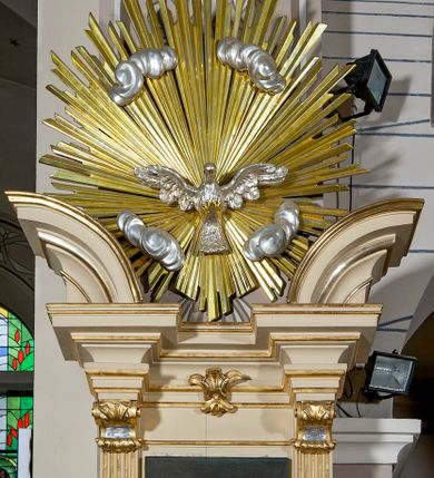 Zdjęcie nr 5: Ambona przyścienna, wisząca, dostępna schodami z podestem. Ich balustrada jest pełna dekorowana płycinami wypełnionymi plakietami z ornamentacją roślinną. Kosz na profilowanym cokole z półwałkiem, na planie prostokąta o wklęsło-wypukłych ściankach wydzielonych spływami z wolutami, dekorowanymi kampanulami i liśćmi akantu. Na wklęsłych ściankach płyciny w kształcie stojącego prostokąta, wypełnione płaskorzeźbionymi, całopostaciowymi przedstawieniami św. Łukasza z lewej i św. Jana Ewangelisty z prawej strony, pod ich stopami kartusze ujęte dekoracją rocaille’ową.  Parapet w postaci profilowanego gzymsu wyłamanego nad spływami. Spód kosza w kształcie wklęsło-wypukłego, odwróconego stożka zakończonego szyszką. Zaplecek w formie wydłużonego prostokąta ujętego kanelowanymi pilastrami. W polu obraz w kształcie stojącego prostokąta z wizerunkiem Chrystusa Dobrego Pasterza. Pilastry podtrzymują profilowane belkowanie wyłamane na ich osiach, na których znajdują się fragmenty przyczółka skierowane na zewnątrz. Między nimi, na ścianie rozbudowane przedstawienie gołębicy Ducha Świętego na tle glorii promienistej  i obłoków.  Struktura w odcieniu kremowym, dekoracja i profile złocone i srebrzone. 