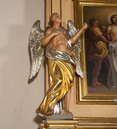 Zdjęcie nr 8: Ołtarz przyścienny, architektoniczny, jednoosiowy, jednokondygnacyjny ze zwieńczeniem. Mensa prostopadłościenna na profilowanym cokole, antepedium dekorowane trzema płycinami z plakietami z ornamentu roślinnego. Tabernakulum architektoniczne, w formie prostopadłościanu na profilowanym cokole, o ujętym wolutami wklęsło-wypukłym zwieńczeniu. Na ścianie frontowej drzwiczki w kształcie stojącego prostokąta zamkniętego łukiem nadwieszonym z uskokiem. Nastawa ołtarzowa ujęta  pilastrami z płycinami ustawionymi na wysokich cokołach, na których wspierają się konsole podtrzymujące rzeźby aniołów. Podpory dźwigają pełne, wyłamane na ich osiach belkowanie, na którym posadowiono figury aniołków. W centrum kondygnacji prostokątna nisza mieszcząca obraz „Męczeństwo św. Bartłomieja”, ujęta prostokątną ramą dekorowaną w czterech miejscach kwitnącymi różami z liśćmi. Między polem obrazowym a belkowaniem kondygnacji unoszony przez dwa anioły kartusz z inskrypcją „ŚWIĘTY / BARTŁOMIEJU / MÓDL SIĘ / ZA NAMI”. Zwieńczenie o kształcie wklęsło-wypukłym, ujęte ulistnionymi wolutami, wypełnione obrazem powtarzającym jego kształt, przedstawiającym Jezusa Chrystusa. Na szczycie krzyż równoramienny o ramionach zakończonych trójlistnie, na tle glorii.  Struktura ołtarza w kolorze kremowym; profile, detale i ornamenty złocone i srebrzone.