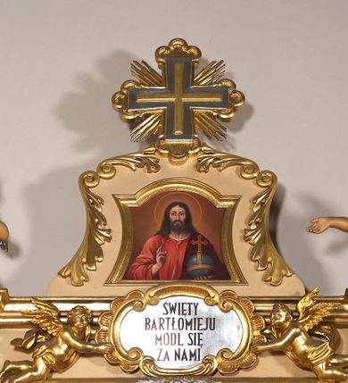 Zdjęcie nr 22: Ołtarz przyścienny, architektoniczny, jednoosiowy, jednokondygnacyjny ze zwieńczeniem. Mensa prostopadłościenna na profilowanym cokole, antepedium dekorowane trzema płycinami z plakietami z ornamentu roślinnego. Tabernakulum architektoniczne, w formie prostopadłościanu na profilowanym cokole, o ujętym wolutami wklęsło-wypukłym zwieńczeniu. Na ścianie frontowej drzwiczki w kształcie stojącego prostokąta zamkniętego łukiem nadwieszonym z uskokiem. Nastawa ołtarzowa ujęta  pilastrami z płycinami ustawionymi na wysokich cokołach, na których wspierają się konsole podtrzymujące rzeźby aniołów. Podpory dźwigają pełne, wyłamane na ich osiach belkowanie, na którym posadowiono figury aniołków. W centrum kondygnacji prostokątna nisza mieszcząca obraz „Męczeństwo św. Bartłomieja”, ujęta prostokątną ramą dekorowaną w czterech miejscach kwitnącymi różami z liśćmi. Między polem obrazowym a belkowaniem kondygnacji unoszony przez dwa anioły kartusz z inskrypcją „ŚWIĘTY / BARTŁOMIEJU / MÓDL SIĘ / ZA NAMI”. Zwieńczenie o kształcie wklęsło-wypukłym, ujęte ulistnionymi wolutami, wypełnione obrazem powtarzającym jego kształt, przedstawiającym Jezusa Chrystusa. Na szczycie krzyż równoramienny o ramionach zakończonych trójlistnie, na tle glorii.  Struktura ołtarza w kolorze kremowym; profile, detale i ornamenty złocone i srebrzone.