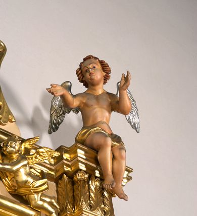 Zdjęcie nr 19: Ołtarz przyścienny, architektoniczny, jednoosiowy, jednokondygnacyjny ze zwieńczeniem. Mensa prostopadłościenna na profilowanym cokole, antepedium dekorowane trzema płycinami z plakietami z ornamentu roślinnego. Tabernakulum architektoniczne, w formie prostopadłościanu na profilowanym cokole, o ujętym wolutami wklęsło-wypukłym zwieńczeniu. Na ścianie frontowej drzwiczki w kształcie stojącego prostokąta zamkniętego łukiem nadwieszonym z uskokiem. Nastawa ołtarzowa ujęta  pilastrami z płycinami ustawionymi na wysokich cokołach, na których wspierają się konsole podtrzymujące rzeźby aniołów. Podpory dźwigają pełne, wyłamane na ich osiach belkowanie, na którym posadowiono figury aniołków. W centrum kondygnacji prostokątna nisza mieszcząca obraz „Męczeństwo św. Bartłomieja”, ujęta prostokątną ramą dekorowaną w czterech miejscach kwitnącymi różami z liśćmi. Między polem obrazowym a belkowaniem kondygnacji unoszony przez dwa anioły kartusz z inskrypcją „ŚWIĘTY / BARTŁOMIEJU / MÓDL SIĘ / ZA NAMI”. Zwieńczenie o kształcie wklęsło-wypukłym, ujęte ulistnionymi wolutami, wypełnione obrazem powtarzającym jego kształt, przedstawiającym Jezusa Chrystusa. Na szczycie krzyż równoramienny o ramionach zakończonych trójlistnie, na tle glorii.  Struktura ołtarza w kolorze kremowym; profile, detale i ornamenty złocone i srebrzone.