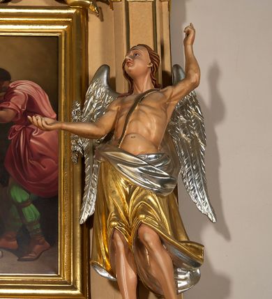 Zdjęcie nr 6: Ołtarz przyścienny, architektoniczny, jednoosiowy, jednokondygnacyjny ze zwieńczeniem. Mensa prostopadłościenna na profilowanym cokole, antepedium dekorowane trzema płycinami z plakietami z ornamentu roślinnego. Tabernakulum architektoniczne, w formie prostopadłościanu na profilowanym cokole, o ujętym wolutami wklęsło-wypukłym zwieńczeniu. Na ścianie frontowej drzwiczki w kształcie stojącego prostokąta zamkniętego łukiem nadwieszonym z uskokiem. Nastawa ołtarzowa ujęta  pilastrami z płycinami ustawionymi na wysokich cokołach, na których wspierają się konsole podtrzymujące rzeźby aniołów. Podpory dźwigają pełne, wyłamane na ich osiach belkowanie, na którym posadowiono figury aniołków. W centrum kondygnacji prostokątna nisza mieszcząca obraz „Męczeństwo św. Bartłomieja”, ujęta prostokątną ramą dekorowaną w czterech miejscach kwitnącymi różami z liśćmi. Między polem obrazowym a belkowaniem kondygnacji unoszony przez dwa anioły kartusz z inskrypcją „ŚWIĘTY / BARTŁOMIEJU / MÓDL SIĘ / ZA NAMI”. Zwieńczenie o kształcie wklęsło-wypukłym, ujęte ulistnionymi wolutami, wypełnione obrazem powtarzającym jego kształt, przedstawiającym Jezusa Chrystusa. Na szczycie krzyż równoramienny o ramionach zakończonych trójlistnie, na tle glorii.  Struktura ołtarza w kolorze kremowym; profile, detale i ornamenty złocone i srebrzone.