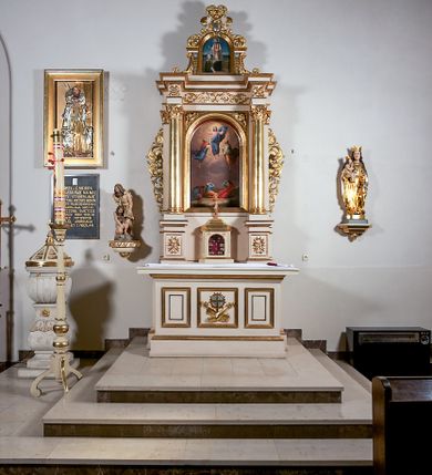Zdjęcie nr 2: Ołtarz przyścienny, architektoniczny, jednoosiowy, jednokondygnacyjny ze zwieńczeniem, z uszakami. Mensa prostopadłościenna na cokole; antepedium dekorowane trzema płycinami, z których środkowa wypełniona emblematem franciszkańskim złożonym ze skrzyżowanych rąk poniżej krzyża w glorii. Tabernakulum architektoniczne, o ściętych narożach podkreślonych lizenami, na profilowanym cokole. W ścianie frontowej nisza w kształcie stojącego prostokąta zamkniętego łukiem pełnym z umocowanymi na czerwonym tle relikwiami. Kondygnację zamyka gzyms i uskokowe zwieńczenie pełniące funkcję podstawy pod krucyfiks. Nastawa ołtarzowa, ujęta kompozytowymi kolumnami ustawionymi na wysokich postumentach zdobionych plakietami roślinnymi. Dźwigają one pełne, wyłamane na ich osiach belkowanie . Fryz wysuniętych części dekorowany rozetami, a cofniętej fragmentem symetrycznej wici. W centrum kondygnacji nisza zamknięta łukiem półkolistym mieszcząca obraz „Przemienienie Pańskie” i wizerunek św. Franciszka na zasuwie. Nisza ujęta prostokątną ramą, której wolne naroża wypełniają uskrzydlone główki anielskie. Kondygnacja ujęta ażurowymi uszakami z wici roślinnej. W zwieńczeniu przedstawienie św. Walentego w formie stojącego prostokąta zamkniętego łukiem pełnym, ujęte pilastrami z cekinami i wolutami podtrzymującymi fragmenty belkowania. Od góry nisza ujęta rzeźbionym, ornamentalnym zwieńczeniem o wklęsło-wypukłym profilu złożonym z ulistnionych wolut ujmujących kartusz z owalnym polem podtrzymujący woluty tworzące kształt serca. 
Struktura ołtarza w kolorze białym; profile, detale, ornamenty i kolumny złocone.
