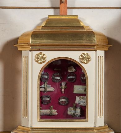 Zdjęcie nr 7: Ołtarz przyścienny, architektoniczny, jednoosiowy, jednokondygnacyjny ze zwieńczeniem, z uszakami. Mensa prostopadłościenna na cokole; antepedium dekorowane trzema płycinami, z których środkowa wypełniona emblematem franciszkańskim złożonym ze skrzyżowanych rąk poniżej krzyża w glorii. Tabernakulum architektoniczne, o ściętych narożach podkreślonych lizenami, na profilowanym cokole. W ścianie frontowej nisza w kształcie stojącego prostokąta zamkniętego łukiem pełnym z umocowanymi na czerwonym tle relikwiami. Kondygnację zamyka gzyms i uskokowe zwieńczenie pełniące funkcję podstawy pod krucyfiks. Nastawa ołtarzowa, ujęta kompozytowymi kolumnami ustawionymi na wysokich postumentach zdobionych plakietami roślinnymi. Dźwigają one pełne, wyłamane na ich osiach belkowanie . Fryz wysuniętych części dekorowany rozetami, a cofniętej fragmentem symetrycznej wici. W centrum kondygnacji nisza zamknięta łukiem półkolistym mieszcząca obraz „Przemienienie Pańskie” i wizerunek św. Franciszka na zasuwie. Nisza ujęta prostokątną ramą, której wolne naroża wypełniają uskrzydlone główki anielskie. Kondygnacja ujęta ażurowymi uszakami z wici roślinnej. W zwieńczeniu przedstawienie św. Walentego w formie stojącego prostokąta zamkniętego łukiem pełnym, ujęte pilastrami z cekinami i wolutami podtrzymującymi fragmenty belkowania. Od góry nisza ujęta rzeźbionym, ornamentalnym zwieńczeniem o wklęsło-wypukłym profilu złożonym z ulistnionych wolut ujmujących kartusz z owalnym polem podtrzymujący woluty tworzące kształt serca. 
Struktura ołtarza w kolorze białym; profile, detale, ornamenty i kolumny złocone.
