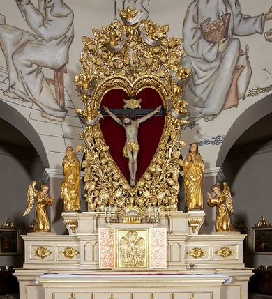 Zdjęcie nr 1: Ołtarz w formie rzeźbionej, ażurowej ramy na trójstopniowym cokole, z prostopadłościenną mensą z antepedium dekorowanym kwadratowymi płycinami z motywem czworoliścia. Na nim prostopadłościenne tabernakulum z drzwiami w kształcie stojącego prostokąta dekorowanymi koszem z chlebem, rybami i chrystogramem. Środkowa część podstawy wypełniona płycinami w kształcie leżących prostokątów z plakietami roślinnymi. Na jej zewnętrznych częściach posadowiono figury klęczących aniołów. Najwyższy stopień węższy, trójosiowy, o osiach zewnętrznych wysuniętych, flankowany konsolami z rzeźbami Matki Boskiej po lewej stronie i św. Jana Ewangelisty po prawej. Centralnie umieszczona rama ujmuje pole w kształcie serca, na tle którego jest eksponowany krucyfiks. Ażur tworzy wić winnej latorośli z kiśćmi winogron, a w nią wkomponowane jest siedem postaci aniołów trzymających banderole z ostatnimi słowami wypowiedzianymi przez Chrystusa wiszącego na krzyżu. Od góry: „Pragnę”, „Niewiasto! Oto syn Twój”, „Oto matka twoja”, „Ojcze odpuść im, / bo nie wiedzą co czynią”, „Zaprawdę powiadam tobie / dziś jeszcze będziesz ze Mną w raju”, „Spełniło się! / Ojcze w ręce Twoje oddaję ducha mojego”, „Boże mój Boże mój / czemużeś mnie opuścił”. Struktura w kolorze kremowym, profile, detale i ornamenty złocone; banderole srebrzone. 