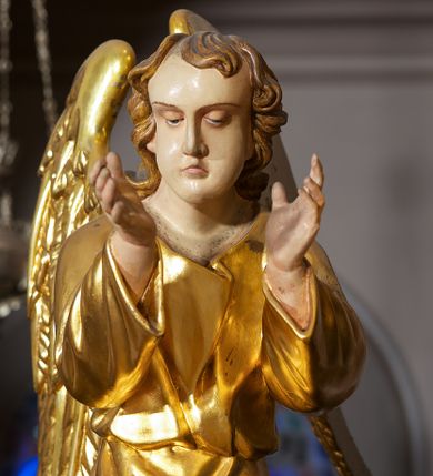 Zdjęcie nr 20: Ołtarz w formie rzeźbionej, ażurowej ramy na trójstopniowym cokole, z prostopadłościenną mensą z antepedium dekorowanym kwadratowymi płycinami z motywem czworoliścia. Na nim prostopadłościenne tabernakulum z drzwiami w kształcie stojącego prostokąta dekorowanymi koszem z chlebem, rybami i chrystogramem. Środkowa część podstawy wypełniona płycinami w kształcie leżących prostokątów z plakietami roślinnymi. Na jej zewnętrznych częściach posadowiono figury klęczących aniołów. Najwyższy stopień węższy, trójosiowy, o osiach zewnętrznych wysuniętych, flankowany konsolami z rzeźbami Matki Boskiej po lewej stronie i św. Jana Ewangelisty po prawej. Centralnie umieszczona rama ujmuje pole w kształcie serca, na tle którego jest eksponowany krucyfiks. Ażur tworzy wić winnej latorośli z kiśćmi winogron, a w nią wkomponowane jest siedem postaci aniołów trzymających banderole z ostatnimi słowami wypowiedzianymi przez Chrystusa wiszącego na krzyżu. Od góry: „Pragnę”, „Niewiasto! Oto syn Twój”, „Oto matka twoja”, „Ojcze odpuść im, / bo nie wiedzą co czynią”, „Zaprawdę powiadam tobie / dziś jeszcze będziesz ze Mną w raju”, „Spełniło się! / Ojcze w ręce Twoje oddaję ducha mojego”, „Boże mój Boże mój / czemużeś mnie opuścił”. Struktura w kolorze kremowym, profile, detale i ornamenty złocone; banderole srebrzone. 