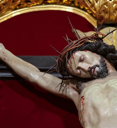 Zdjęcie nr 7: Ołtarz w formie rzeźbionej, ażurowej ramy na trójstopniowym cokole, z prostopadłościenną mensą z antepedium dekorowanym kwadratowymi płycinami z motywem czworoliścia. Na nim prostopadłościenne tabernakulum z drzwiami w kształcie stojącego prostokąta dekorowanymi koszem z chlebem, rybami i chrystogramem. Środkowa część podstawy wypełniona płycinami w kształcie leżących prostokątów z plakietami roślinnymi. Na jej zewnętrznych częściach posadowiono figury klęczących aniołów. Najwyższy stopień węższy, trójosiowy, o osiach zewnętrznych wysuniętych, flankowany konsolami z rzeźbami Matki Boskiej po lewej stronie i św. Jana Ewangelisty po prawej. Centralnie umieszczona rama ujmuje pole w kształcie serca, na tle którego jest eksponowany krucyfiks. Ażur tworzy wić winnej latorośli z kiśćmi winogron, a w nią wkomponowane jest siedem postaci aniołów trzymających banderole z ostatnimi słowami wypowiedzianymi przez Chrystusa wiszącego na krzyżu. Od góry: „Pragnę”, „Niewiasto! Oto syn Twój”, „Oto matka twoja”, „Ojcze odpuść im, / bo nie wiedzą co czynią”, „Zaprawdę powiadam tobie / dziś jeszcze będziesz ze Mną w raju”, „Spełniło się! / Ojcze w ręce Twoje oddaję ducha mojego”, „Boże mój Boże mój / czemużeś mnie opuścił”. Struktura w kolorze kremowym, profile, detale i ornamenty złocone; banderole srebrzone. 