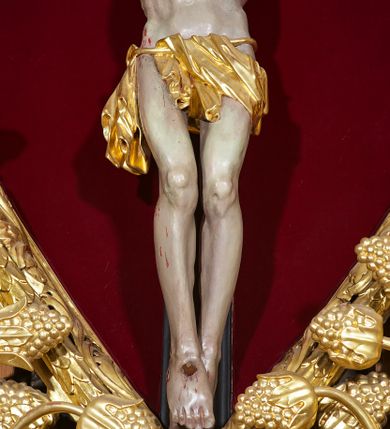 Zdjęcie nr 11: Ołtarz w formie rzeźbionej, ażurowej ramy na trójstopniowym cokole, z prostopadłościenną mensą z antepedium dekorowanym kwadratowymi płycinami z motywem czworoliścia. Na nim prostopadłościenne tabernakulum z drzwiami w kształcie stojącego prostokąta dekorowanymi koszem z chlebem, rybami i chrystogramem. Środkowa część podstawy wypełniona płycinami w kształcie leżących prostokątów z plakietami roślinnymi. Na jej zewnętrznych częściach posadowiono figury klęczących aniołów. Najwyższy stopień węższy, trójosiowy, o osiach zewnętrznych wysuniętych, flankowany konsolami z rzeźbami Matki Boskiej po lewej stronie i św. Jana Ewangelisty po prawej. Centralnie umieszczona rama ujmuje pole w kształcie serca, na tle którego jest eksponowany krucyfiks. Ażur tworzy wić winnej latorośli z kiśćmi winogron, a w nią wkomponowane jest siedem postaci aniołów trzymających banderole z ostatnimi słowami wypowiedzianymi przez Chrystusa wiszącego na krzyżu. Od góry: „Pragnę”, „Niewiasto! Oto syn Twój”, „Oto matka twoja”, „Ojcze odpuść im, / bo nie wiedzą co czynią”, „Zaprawdę powiadam tobie / dziś jeszcze będziesz ze Mną w raju”, „Spełniło się! / Ojcze w ręce Twoje oddaję ducha mojego”, „Boże mój Boże mój / czemużeś mnie opuścił”. Struktura w kolorze kremowym, profile, detale i ornamenty złocone; banderole srebrzone. 